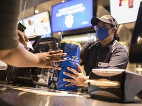 A Cineplex employee serves customers popcorn and other snacks at a Cineplex theatre in Toronto on Wednesday, Aug. 26, 2020.
