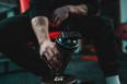 Close up on hand of unknown caucasian man holding dark supplement shaker while sitting at gym during training copy space selective focus