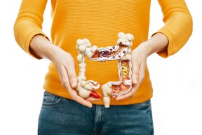 Treatment of crohns disease, flatulence, indigestion. Woman holds in front of her anatomical model of the colon, she has constipation and abdominal pain