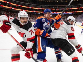 New Jersey Devils' Jonas Siegenthaler (71) and John Marino (6) battle for the puck with Edmonton Oilers' Connor McDavid (97) during second period NHL action in Edmonton on Thursday, November 3, 2022.THE CANADIAN PRESS/Jason Franson