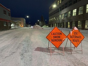 Snow removal signs and snow piled in the street are shown in Yellowknife, N.W.T., on Friday, Nov. 25, 2022. Residents and city staff in the Northwest Territories capital are struggling to keep up with an onslaught of snow.
