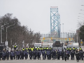 Police walk the line to remove all truckers and supporters in Windsor, Ont., Sunday, Feb. 13, 2022.