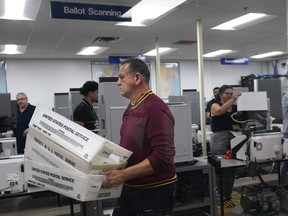 Workers organize vote-by-mail ballots for scanning during the midterm election at the Miami-Dade County Elections Department, Tuesday, Nov. 8, 2022, in Miami.