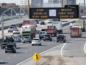 Traffic on Highway 401 in Toronto passes under a COVID-19 sign on Monday April 6, 2020.
