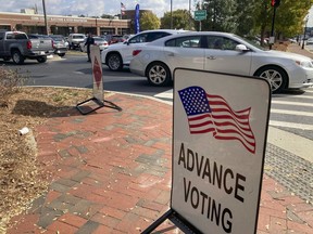 A sign showing the way for voters stands outside a Cobb County voting building during the first day of early voting, Monday, Oct. 17, 2022, in Marietta, Ga.
