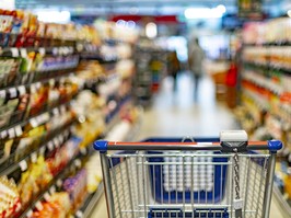 A shopping cart by a store shelf in a supermarket