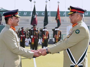 In this photo released by Army's public relations wing 'Inter Services Public Relations', Pakistan's outgoing Army Chief Gen. Qamar Javed Bajwa, right, hands over a ceremonial baton to his successor Gen. Asim Munir during the Change of Command ceremony, in Rawalpindi, Pakistan, Tuesday, Nov. 29, 2022. Pakistan's new army chief Munir, took command of the country's armed forces amid a deepening political rift between the government and the popular opposition leader, as well as a renewed threat from a key militant group that has been behind scores of deadly attacks over 15 years. (Inter Services Public Relations via AP)