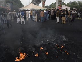 Supporters of former Pakistani Prime Minister Imran Khan's party, 'Pakistan Tehreek-e-Insaf' block a main road during a protest to condemn a shooting incident on their leader's convoy, in Rawalpindi, Pakistan, Tuesday, Nov. 8, 2022. Khan postponed the resumption of his protest march on the country's capital meant to challenge his successor's government, his party said Tuesday.