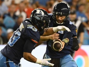 Toronto Argonauts quarterback McLeod Bethel-Thompson hands off the ball to running back Andrew Harris during second half CFL football action against the Hamilton Tiger-Cats in Toronto on Saturday, Aug. 6, 2022.&ampnbsp;Harris has resumed practising with the Toronto Argonauts.