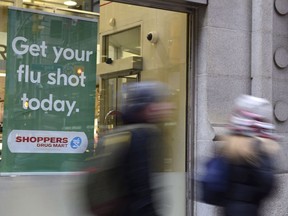 People walk past a sign for flu shots in Toronto on Jan. 9, 2018. A top doctor at the children's hospital in Winnipeg says the facility has seen three times the normal number of children with the seasonal flu this year.
