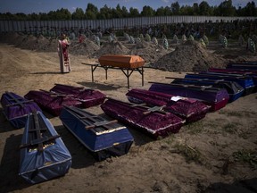 A priest blesses coffins with unidentified civilian bodies, who died on the territory of the Bucha community during the Russian occupation period in February-March 2022, during a funeral in Bucha, near Kyiv, Ukraine, on September 2, 2022.
