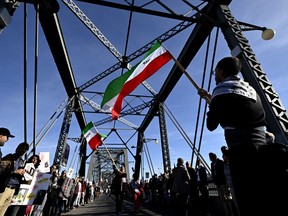 Demonstrators wave colours of the flag of Iran as they participate in a worldwide "human chain" along the Alexandra Bridge joining Ottawa and Gatineau, Que., organized by the Association of Families of Flight PS752 Victims in solidarity with antigovernment protesters in Iran, on October 29, 2022.