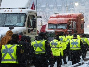 Police walk as heavy snow falls on the 21st day of a protest against COVID-19 measures that has grown into a broader anti-government protest, in Ottawa, on Thursday, Feb. 17, 2022.