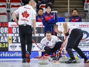 Canada skip Brad Gushue, centre bottom, directs his teammates, lead Geoff Walker, left, and second EJ Harnden, right, as Korea skip Jeong Byeongjin looks on during the men's gold medal game at the Pan Continental Curling Championships in Calgary, Alta., Sunday, Nov. 6, 2022.