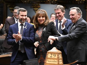 Elected House Speaker Nathalie Roy is carried to her seat by Quebec Premier Francois Legault, right, as Quebec Solidaire Leader Gabriel Nadeau-Dubois, left, and Quebec Liberal Party interim Leader Marc Tanguay applaud, Tuesday, November 29, 2022 at the legislature in Quebec City. The legislature resumes as the 43nd Legislature begins.