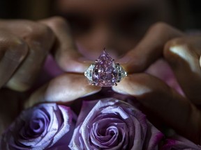 A Christie's employee displays a pink diamond called "The Fortune Pink" of 18,18 carat, during a preview at Christie's, in Geneva, Switzerland, Wednesday, Nov. 2, 2022. The pear-shaped 18-carat pink diamond is set to be sold at auction on Tuesday and is expected to fetch between $25 million and $35 million.