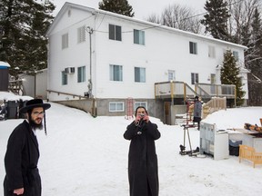 Members of the ultra-orthodox Jewish sect Lev Tahor, stood and took photos outside their home with their furniture as they wait to for a moving truck to arrive in the town of Sainte-Agathe-des-Monts in 2013.