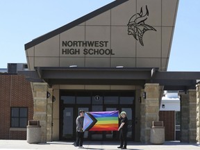 FILE - Former Viking Saga newspaper staff members Marcus Pennell, left, and Emma Smith display a pride flag outside of Northwest High School in Grand Island, Neb., July 20, 2022. A Nebraska public school district that shuttered the school's award-winning student newspaper following its issue of an LGBTQ-focused edition has agreed to bring back the newspaper next year in digital form.