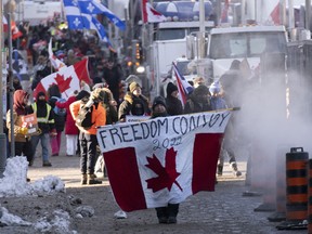 Protesters participating in a cross-country truck convoy protesting measures taken by authorities to curb the spread of COVID-19 and vaccine mandates walk near Parliament Hill in Ottawa.