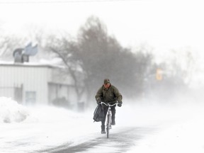 A man rides his bike down the street in Fort Erie, Ont., during an early winter storm that delivered high winds and large amounts of snow across southern Ontario and western New York, Saturday, Nov. 19, 2022. Canadians enjoying a brief relief from the onset of winter-like conditions may want to enjoy the temperatures while they can because The Weather Network is forecasting a colder than normal start to winter across most of the country.