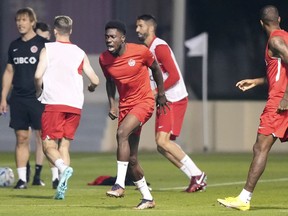 Canada star Alphonso Davies, center, grimaces during a warmup drill at the World Cup in Doha, Qatar during on Monday, November 21, 2022.