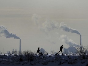 People cross-country ski in the cold weather as an industrial plant is shown in the back ground in Toronto on Friday, Feb. 4, 2022. Environment Minister Steven Guilbeault says Canada is issuing a challenge to the rest of the world to expand the use of carbon pricing in the fight against greenhouse gas emissions.