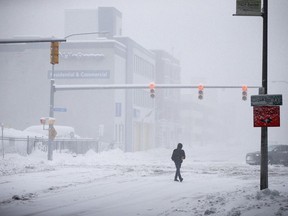 A person crosses Ellicott Street as snow falls Friday, Nov. 18, 2022, in Buffalo, N.Y. A dangerous lake-effect snowstorm paralyzed parts of western and northern New York, with nearly 2 feet of snow already on the ground in some places and possibly much more on the way.