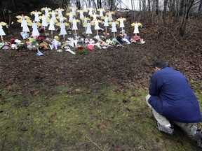 FILE - In this Dec. 18, 2012, file photo, Robert Soltis, of Newtown, Conn., pauses after making the sign of the cross at a memorial to Sandy Hook Elementary School shooting victims in Newtown. A memorial to the 20 first graders and six educators killed in the Sandy Hook Elementary School shooting opened to the public Sunday, Nov. 13, 2022, a month before the 10th anniversary of the massacre.