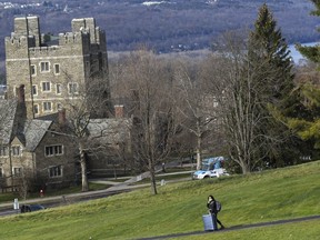 FILE - A Cornell University student walks along the campus in Ithaca, N.Y., on Dec. 16, 2021, with luggage in tow. Cornell University has announced the temporary suspension of fraternity parties after a student reported being sexually assaulted on Sunday, Nov. 6, 2022, and four others were reportedly drugged at off-campus housing in recent weeks, university leaders said this week.