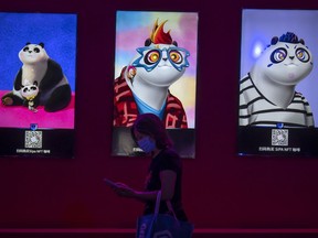 FILE - A visitor wearing a face mask walks past artwork displayed at an NFT (non-fungible token)-themed coffee shop at the China International Fair for Trade in Services (CIFTIS) in Beijing, Sept. 3, 2022. Fidelity Charitable, the nation's largest grant maker, is getting into NFTs, the digital images that are registered on the blockchain, despite a torrent of bad news from adjacent world of cryptocurrencies.