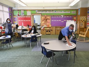 A man sanitizes table surfaces in a kindergarten classroom in Scarborough, Ont., on Monday, September 14, 2020. Canada's largest school board said it will close schools on Friday in response to a planned walkout from Ontario education workers protesting legislation that imposes a contract and bans a strike.
