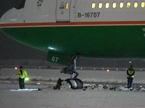 Workers are seen around an EVA Air Boeing 777 aircraft that went off a taxiway onto soft ground after landing at Vancouver International Airport from Taipei during a snowstorm on Tuesday, in Richmond, B.C., during the early morning hours of Wednesday, November 30, 2022. Nobody was injured and passengers were deplaned and shuttled to the terminal on buses after being stuck on the plane for three hours. Snowfall, winter storm and arctic outflow warnings were in effect for most of British Columbia as a powerful storm packing frigid winds moved through the province.