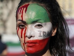 A woman is painted on a her face during a protest against the death of Mahsa Amini, a woman who died while in police custody in Iran, during a rally in central Rome, Saturday, Oct. 29, 2022.