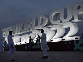 People pose for a photograph with a FIFA World Cup sign in Doha, Qatar, Thursday, Nov. 17, 2022. The day after its win over Japan in Dubai in its final World Cup warmup, Canada had no media availability Friday -- leaving time to recover, assess and prepare for Wednesday's tournament opener against second-ranked Belgium. But while Canada laid low, the World Cup was hard to miss in downtown Doha.