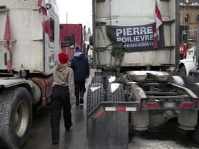 People walk past a truck bearing a flag calling for Conservative MP Pierre Poilievre to become Prime Minister, during the "Freedom Convoy" protest, in Ottawa, on Feb. 16, 2022. Poilievre says he stands by his support of the convoy, but will wait until a public inquiry on the matter is over before weighing in on evidence.