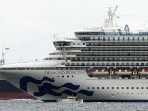 FILE - A small boat navigates near the Diamond Princess cruise ship anchoring off the Yokohama Port, near Tokyo on Feb. 4, 2020. Japan is lifting a more than 2 1/2-year ban on international cruise ships that was imposed following a deadly coronavirus outbreak on the cruise ship Diamond Princess at the beginning of the pandemic.