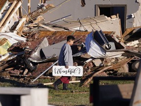 Logan Johnson, 11, carries a sign that reads "Thankful" after he recovered it from his family's destroyed home after a tornado hit in Powderly, Texas, Saturday, Nov. 5, 2022.