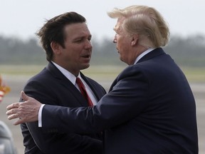 FILE - President Donald Trump shakes hands with Florida Gov. Ron DeSantis as he arrives at Tyndall Air Force Base to view damage from Hurricane Michael, and attend a political rally, May 8, 2019, at Tyndall Air Force Base, Fla.