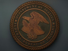 The seal for the Federal Bureau of Prisons is seen at Federal Bureau of Prisons headquarters in Washington, Oct. 24, 2022. A federal prison inmate was able to obtain a firearm at a prison in Arizona and then pulled it out in a visitation room and pointed it at a visitor's head. The Associated Press has learned the  weapon misfired and the female visitor was uninjured in the Nov. 13, incident at the Federal Correctional Institution in Tucson.
