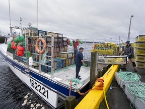 Crew members load pots and buoys in Port Medway, N.S., on Monday, Nov. 28, 2022. Boats in Lobster Fishing Area 33 will start their season on Tuesday, but neighbouring LFA 34 is still delayed by weather.