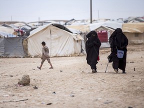FILE - Women walk in the al-Hol camp that houses some 60,000 refugees, including families and supporters of the Islamic State group, many of them foreign nationals, in Hasakeh province, Syria, May 1, 2021. The Syrian Observatory for Human Rights and local officials said Tuesday, Nov. 15, 2022 that the beheaded bodies of two Egyptian girls were found Tuesday in a sprawling camp in northeastern Syria housing tens of thousands of women and children linked to the Islamic State group.