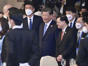 In this photo released by Hong Kong Government Information Services, Hong Kong Chief Executive John Lee, center right, stands next to Chinese President Xi Jinping, center, during a gala dinner at the Asia-Pacific Economic Cooperation (APEC) Summit in Bangkok, Thailand on Nov. 17, 2022. The Hong Kong government said Monday, Nov. 21, 2022 that leader John Lee tested positive for COVID-19 after returning from the Asia-Pacific Economic Cooperation meetings in Thailand. (Hong Kong Government Information Services via AP)