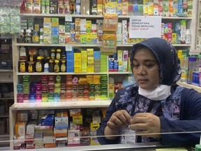 An employee waits for customers at a pharmacy in Jakarta, Indonesia, Tuesday, Nov. 1, 2022. Indonesian authorities have revoked the licenses of two pharmaceutical companies producing syrup-type medicines following the deaths of a number of children due to acute kidney injury, officials said Tuesday.