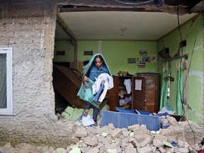 A man collects clothings from his damaged house following an earthquake in Cianjur, West Java, Indonesia Tuesday, Nov. 22, 2022.