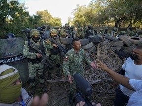 FILE - Residents who are fed up with the army's strategy of simply separating the Jalisco and the Michoacan-based Viagras gangs, confront Mexican soldiers taking cover behind a barricade of car tires, in Loma Blanca, Mexico, Tuesday, Nov. 16, 2021. Mexico's Supreme Court upheld on Tuesday, Nov. 29, 2022, a constitutional change that allows the military to continue in law enforcement duties until 2028.