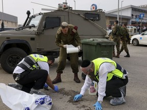 Members of Israeli Zaka Rescue and Recovery team and an Israeli soldier clean blood from the site of an attack, at the Ariel Industrial Zone, near the West Bank Jewish settlement of Ariel, Tuesday, Nov. 15, 2022. A Palestinian killed two Israelis and wounded four others in an attack in a settlement in the occupied West Bank on Tuesday before he was shot and killed by Israeli security personnel, Israeli paramedics and Palestinian officials said.