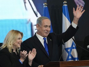 Benjamin Netanyahu, former Israeli Prime Minister and the head of Likud party, accompanied by his wife Sara waves to his supporters after first exit poll results for the Israeli Parliamentary election at his party's headquarters in Jerusalem, Wednesday, Nov. 2, 2022.