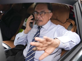 Opposition leader Anwar Ibrahim, talks on a phone as he leaves his office in Kuala Lumpur, Malaysia, Tuesday, Nov. 22, 2022. Malaysia's election uncertainty deepened Tuesday after a political bloc refused to support either reformist leader Anwar Ibrahim or rival Malay nationalist Muhyiddin Yassin as prime minister, three days after divisive polls produced no outright winner.