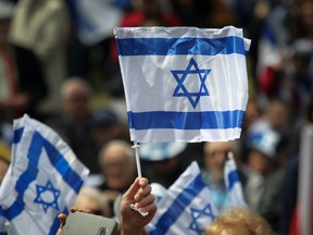 A flag of Israel is held aloft at Place du Canada in Montreal Thursday, May 9, 2019 during Yom Ha’atzmaut  celebrations. It was the 71st  Independence day of the country. (John Kenney / MONTREAL GAZETTE)