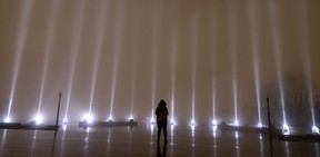 A lone woman is seen taking a moment of silence in front of 14 beams of white light during Tuesday ceremonies to mark the anniversary of the massacre at Ecole Polytechnique in Montreal. The Dec. 6, 1989 massacre saw a gunman charge into the school with the explicit intention of killing as many women as possible. The youngest victim, Annie Turcotte, would have been 53 this year.